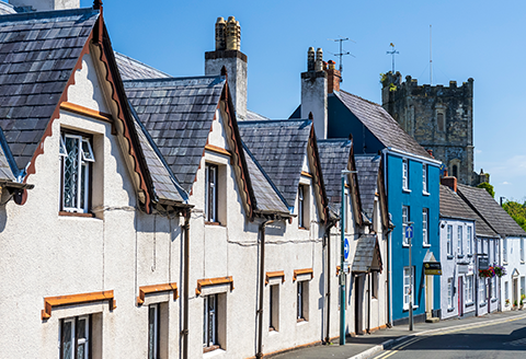 A row of rooftops can be seen leading to a church bell tower. A bright blue sky completes the frame.)