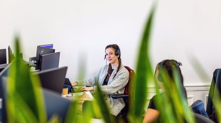 A female support team worker using a headset and desktop computer. 