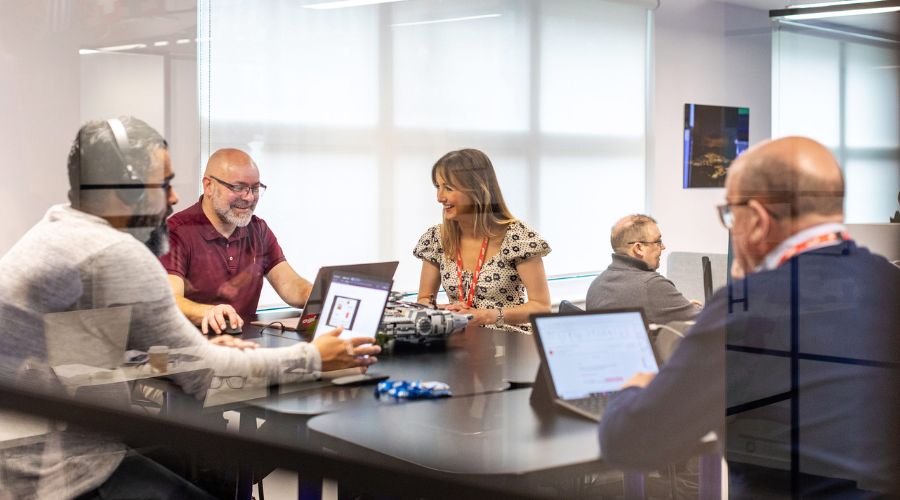 Team members with laptops discussing more about the 2025 digital switchover. 