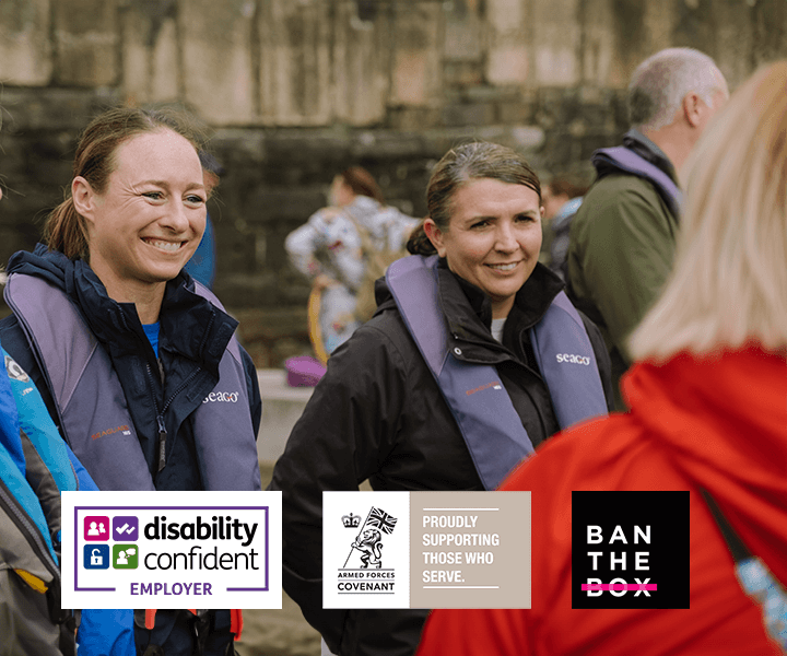 Two people in life jackets outside getting ready to board a boat. They are smiling.